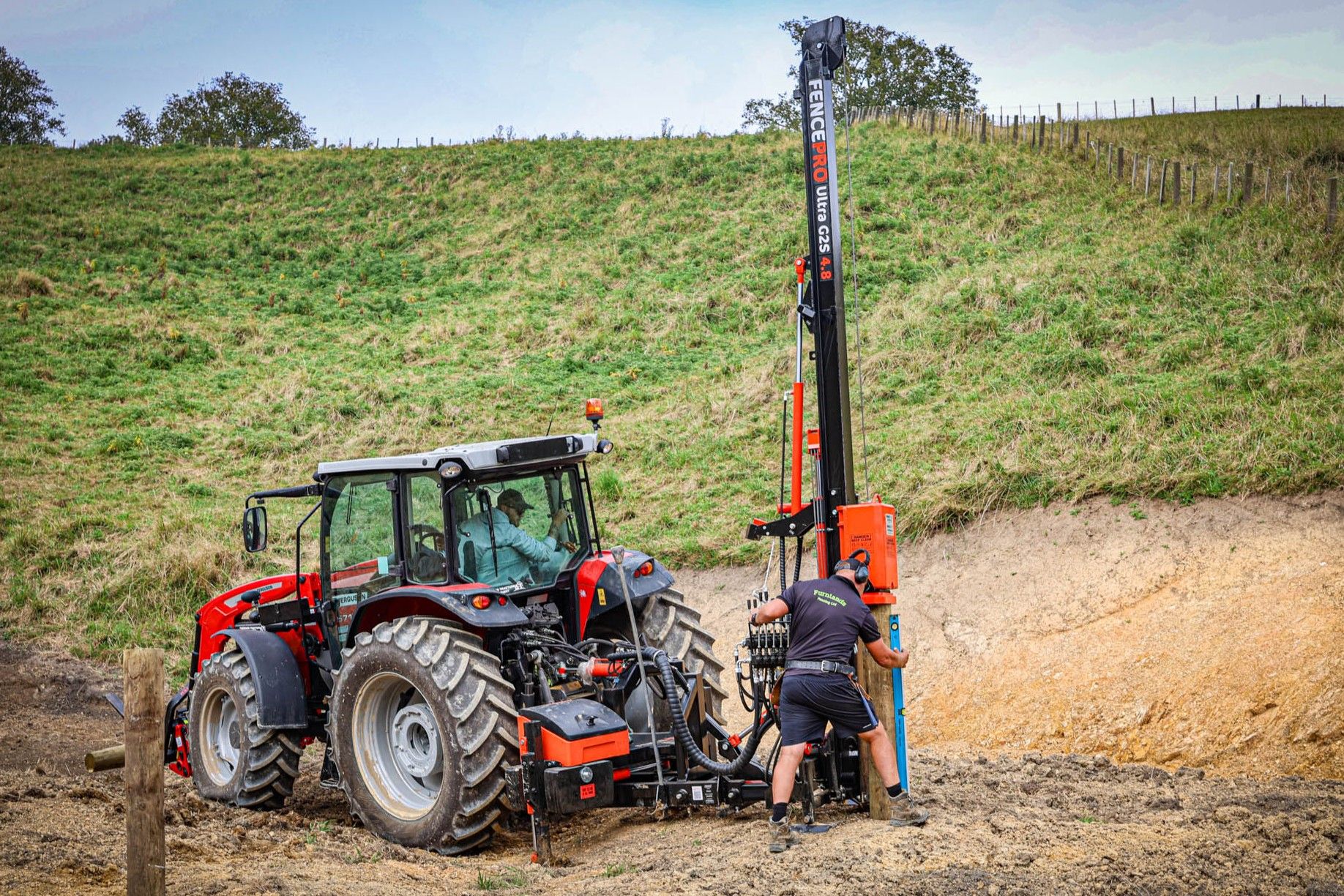 Fencing contractor using a FencePro PB650 post driver base rotated 90° out the back of the tractor.