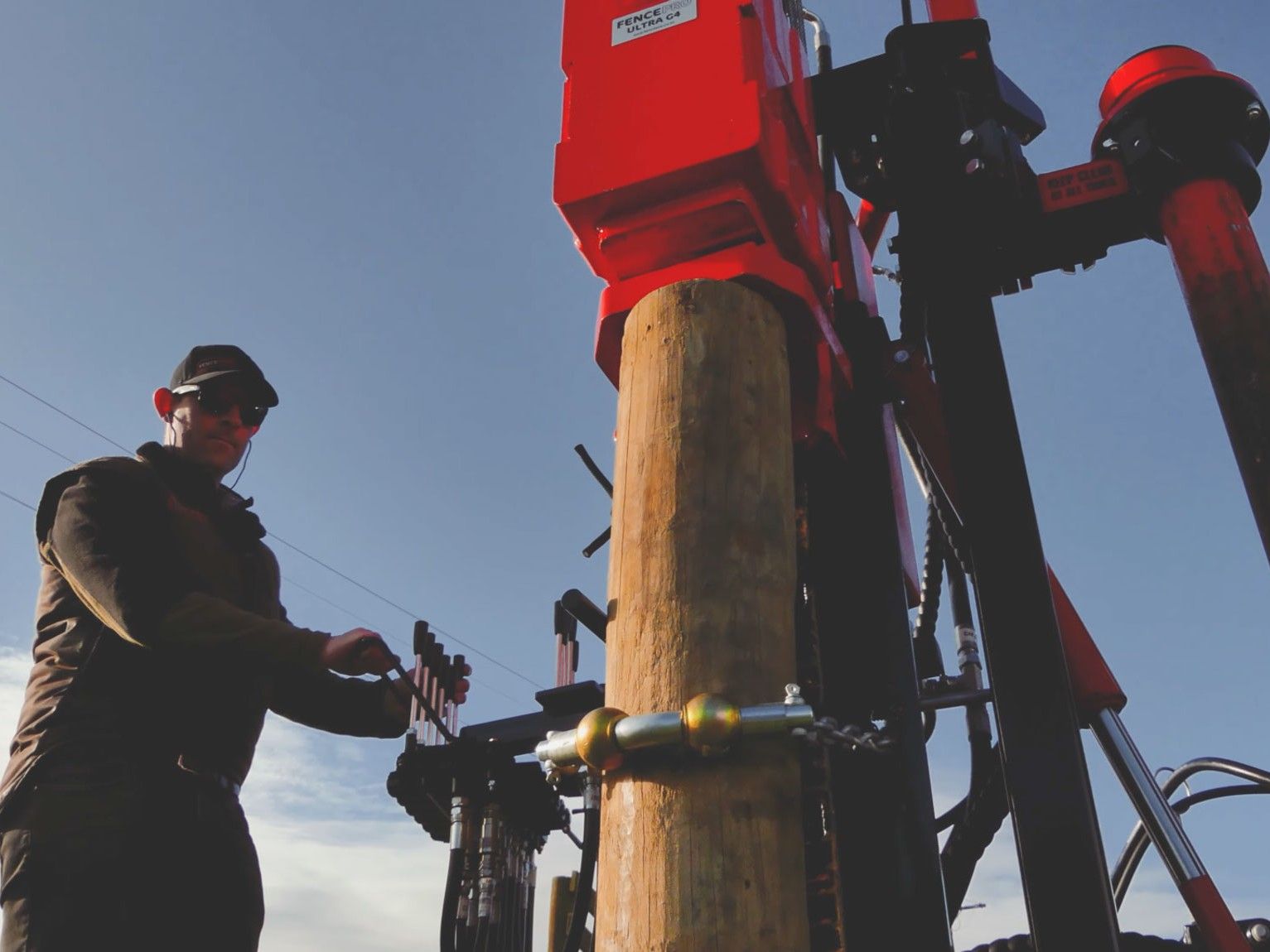 Pin & Chain Post Steering System with roller bar kit in action — holding a post firmly against the FencePro Ultra G4 hydraulic post driver mast. The roller bar keeps the chain running smooth and free from binding.