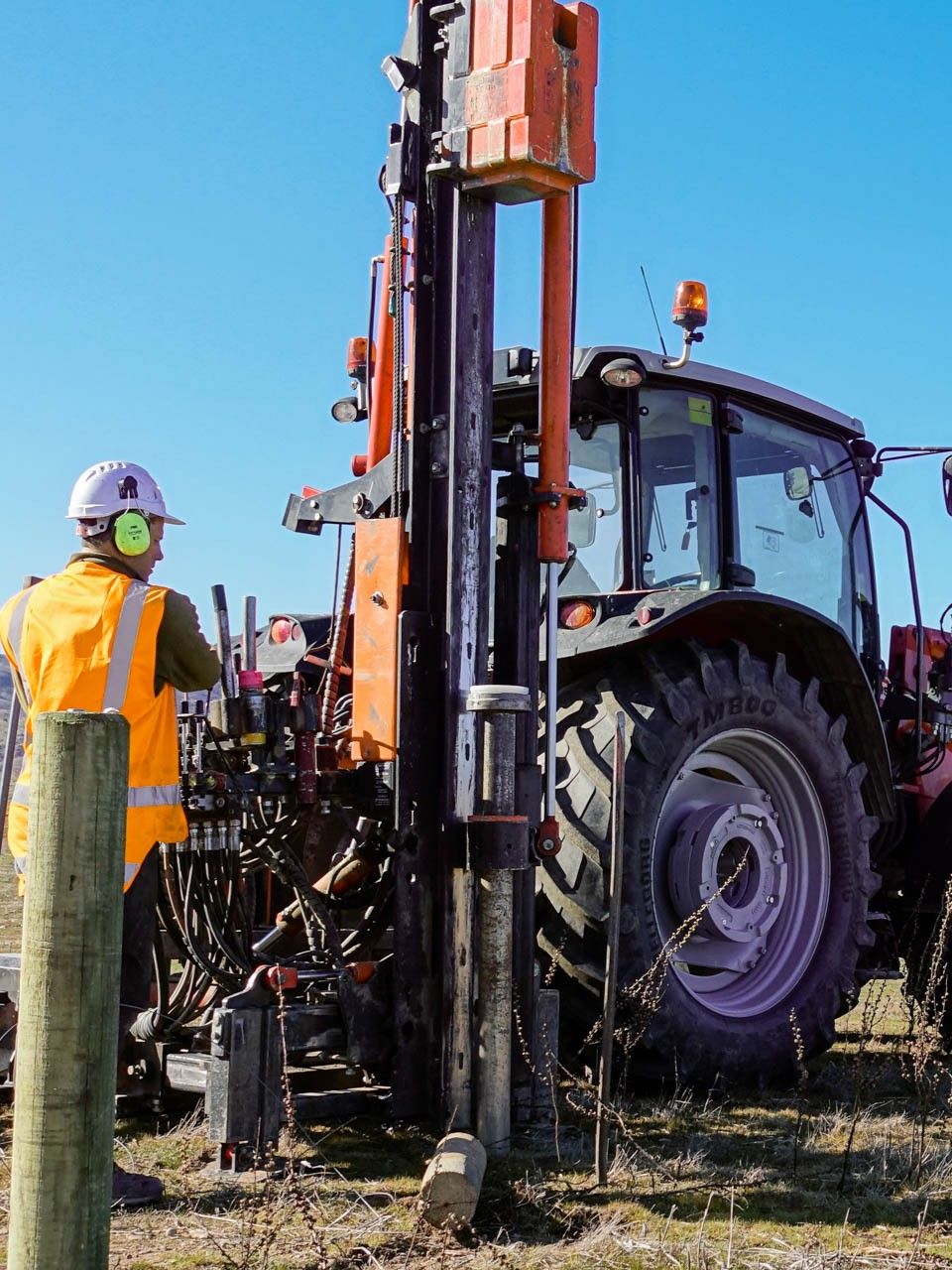 Otago fencing contractor using far-side hydraulically positioned FencePro UltraGlide rockspike kit on tractor, punching pilot holes in stony rock conditions