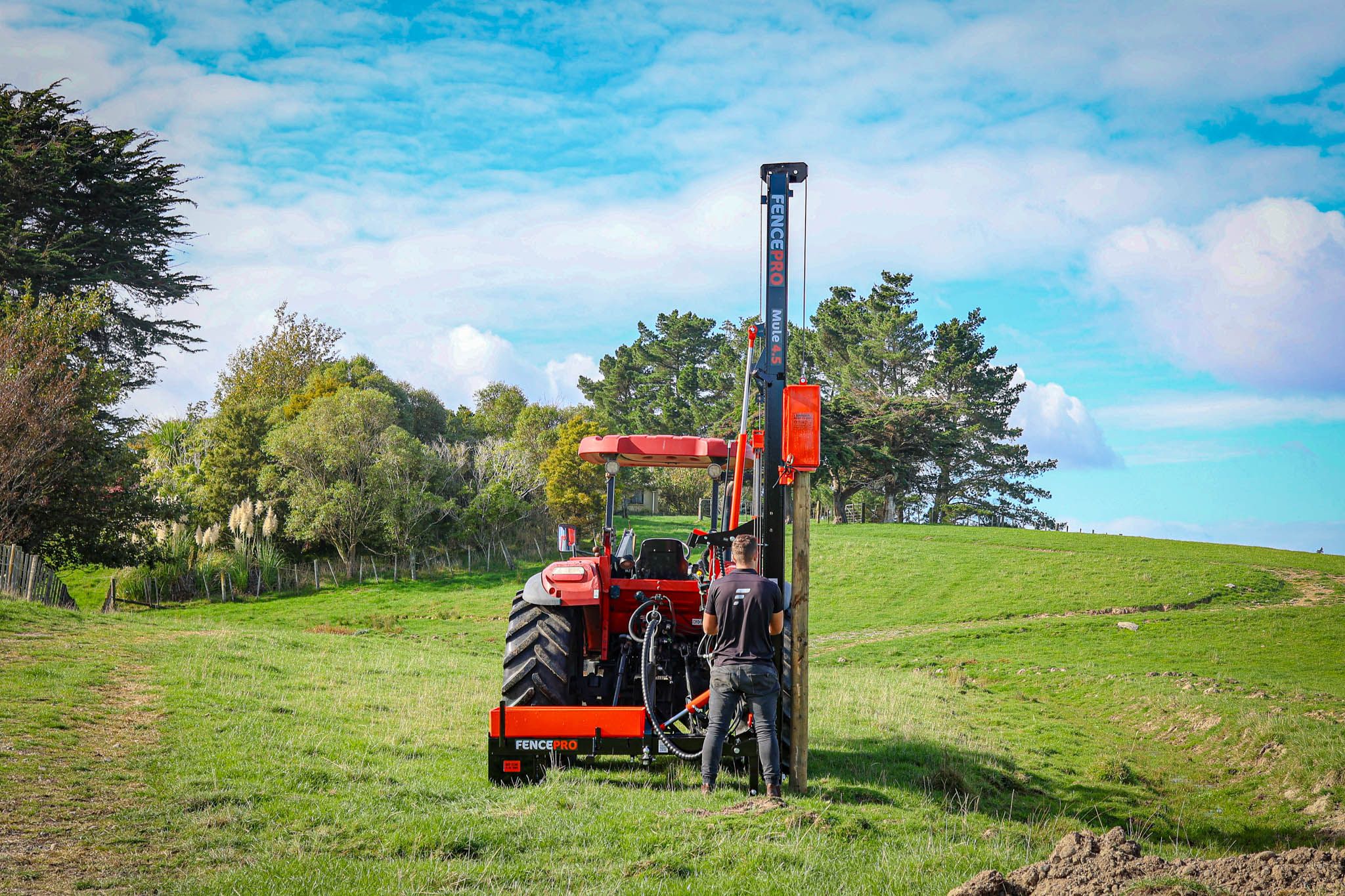 FencePro Mule post driver with 4.5m hydraulic hinge mast in work position, side mount base, driving a fence post.