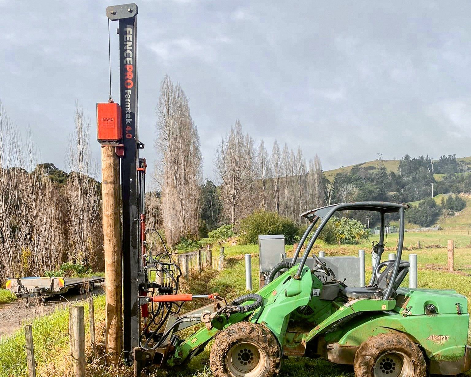 FencePro Farmtek post driver ramming a strainer post during farm fencing work in New Zealand.