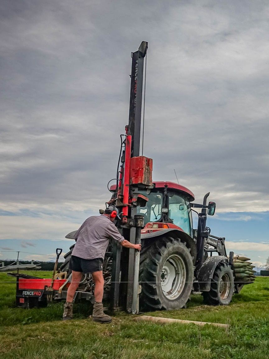 Fencing contractor checking alignment on near-side mounted FencePro UltraGlide rockspike kit, adjusting the post driver tilts for a straight pilot hole.