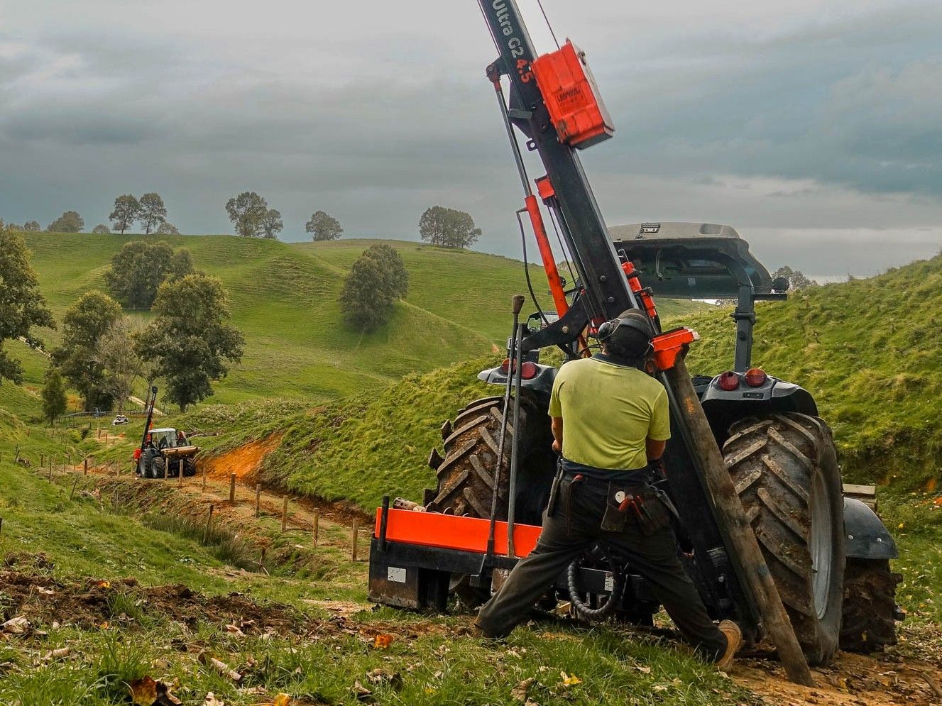 Contractor operating FencePro SM900 Sidemount Base in King Country with post driver, spade, and hand rammer stored on base.