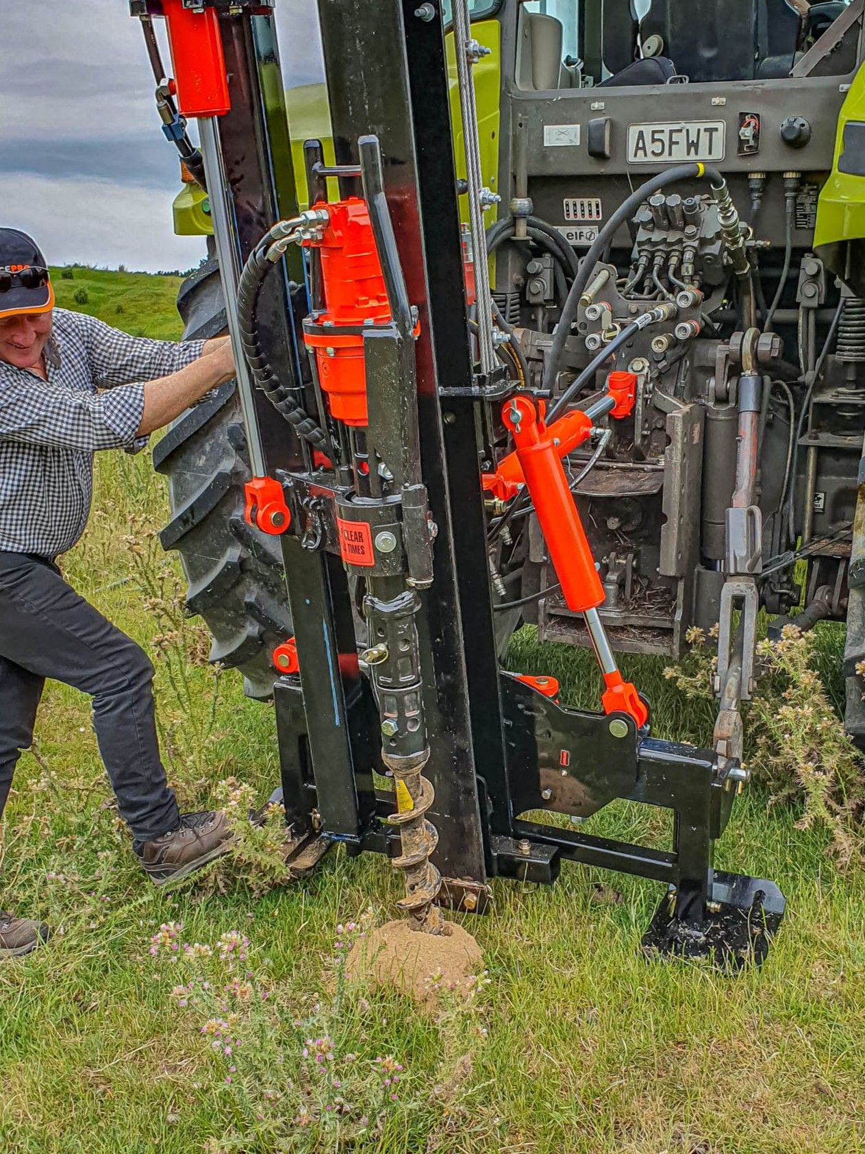 FencePro rock drill attachment drilling a pilot hole using a tractor mounted post driver on NZ Farm